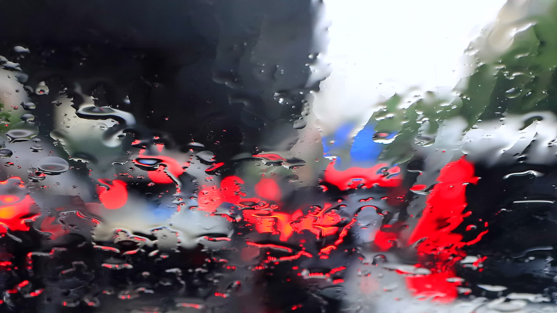前风挡玻璃雨幕和虚化的前车4K视频的预览图