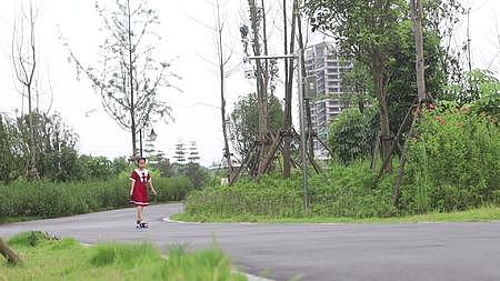 公园里小女孩穿红色连衣裙玩滑板过弯道视频的预览图
