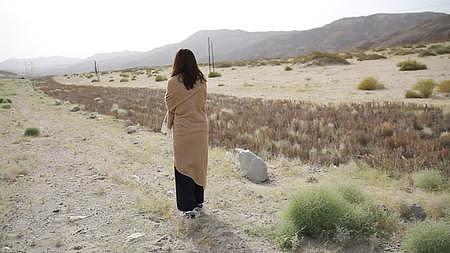 新疆戈壁滩沙漠无人区年轻女性女生走路背影实景拍摄视频的预览图