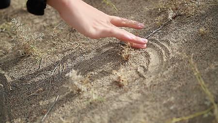 新疆沙漠沙丘女生手部特写沙地画画实景拍摄视频的预览图