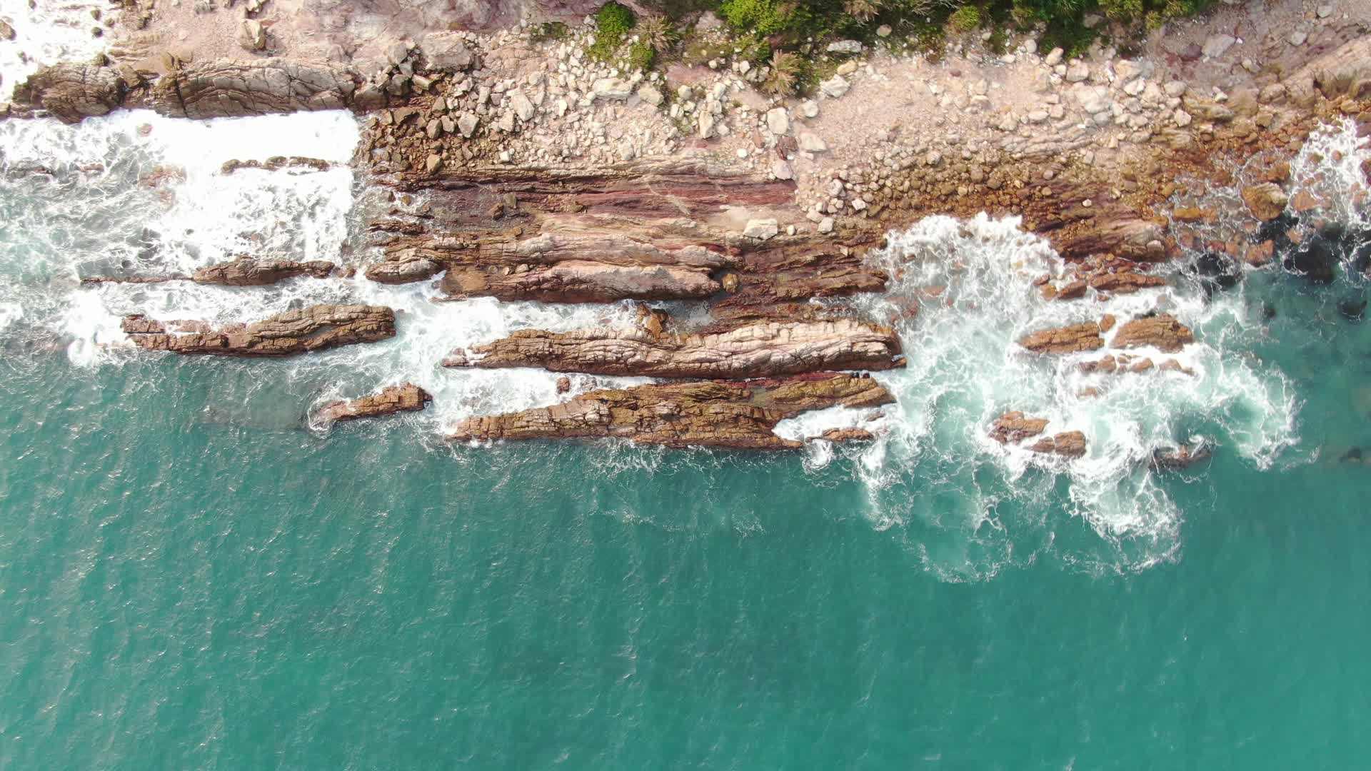 俯拍海浪拍打礁石沙滩视频的预览图