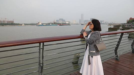 站在城市江边看都市风景思考的女人侧面视频的预览图