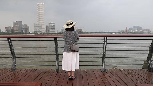 站在城市江边看都市风景思考的女人背影视频的预览图