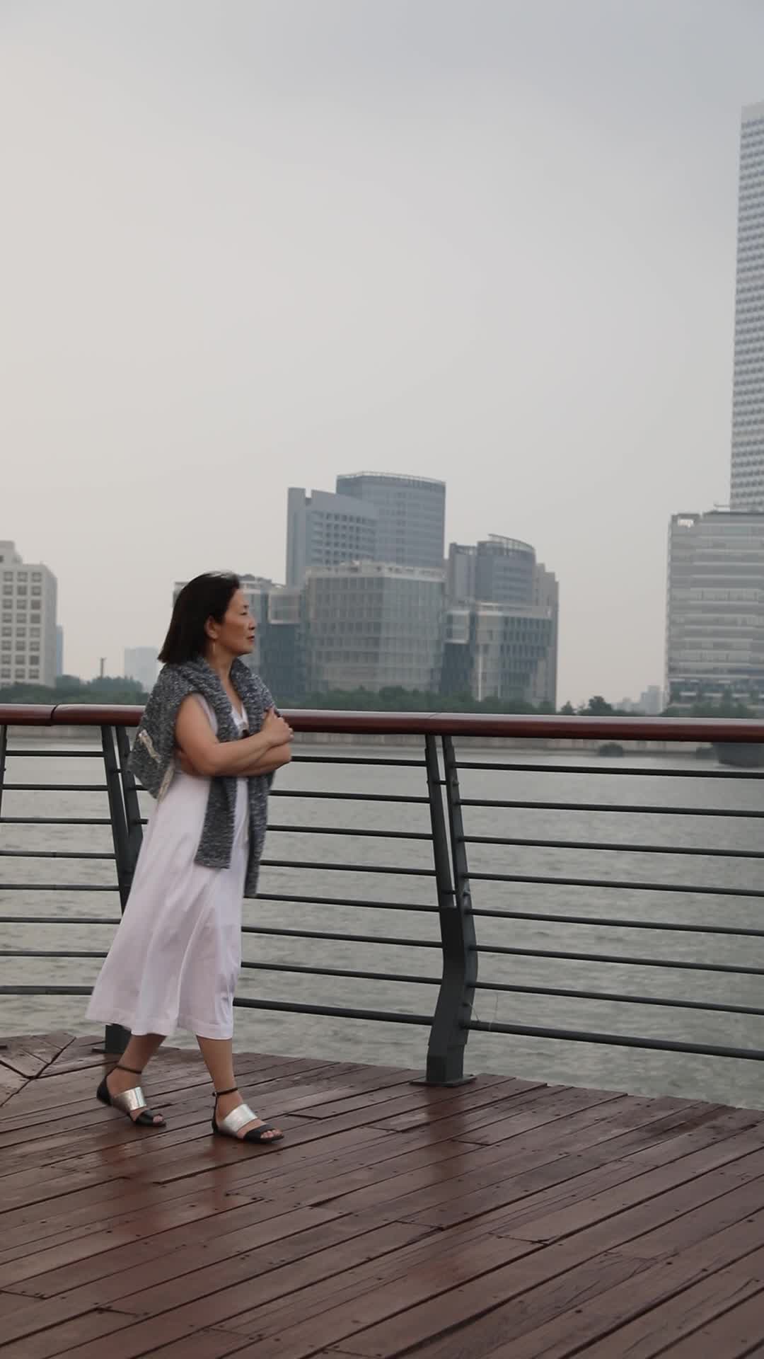 走在城市江边看都市风景思考的女人背影视频的预览图