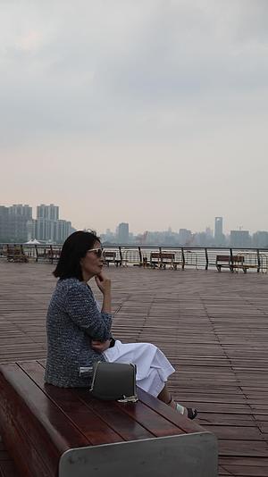 坐在城市江边看都市风景思考的女人背影视频的预览图