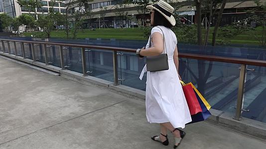 拿着购物袋走在街道上的时尚女人视频的预览图