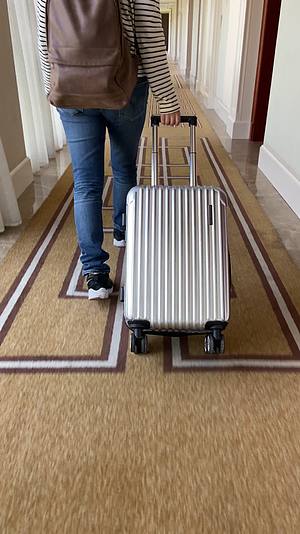一个女人拉着行李箱走在酒店走廊视频的预览图