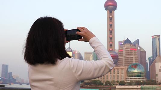 一个女人用手机拍摄陆家嘴城市风光视频的预览图