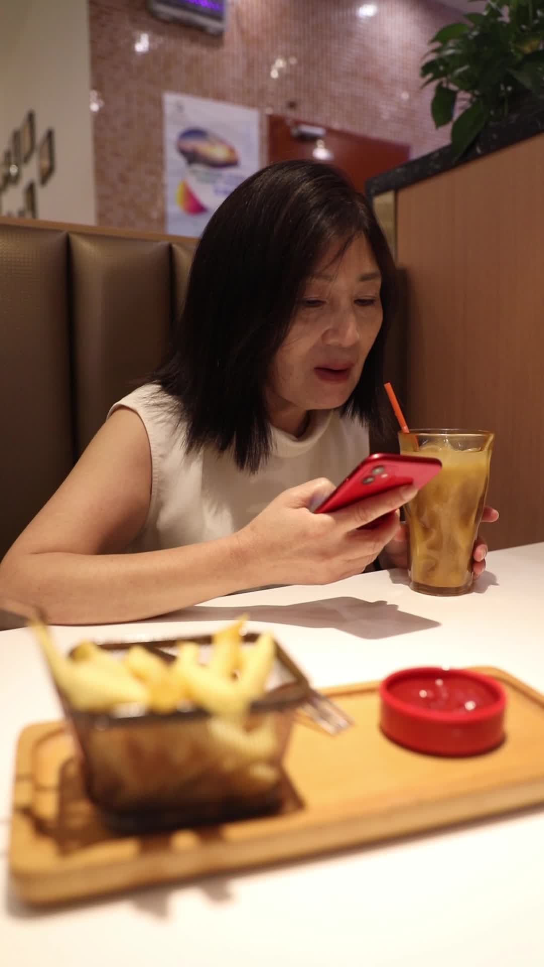 一个女人在餐厅吃饭时使用手机视频的预览图