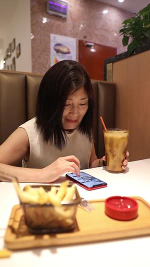 一个女人在餐厅吃饭时使用手机视频的预览图