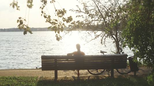 实拍夕阳下的湖面骑行后休闲的人视频的预览图