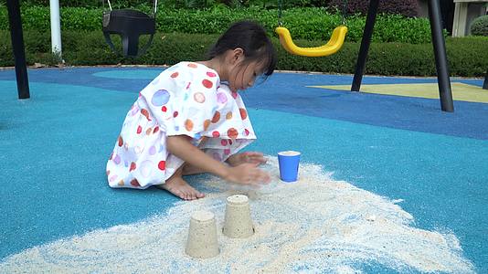 在蓝色地面上玩沙子的小女孩视频的预览图