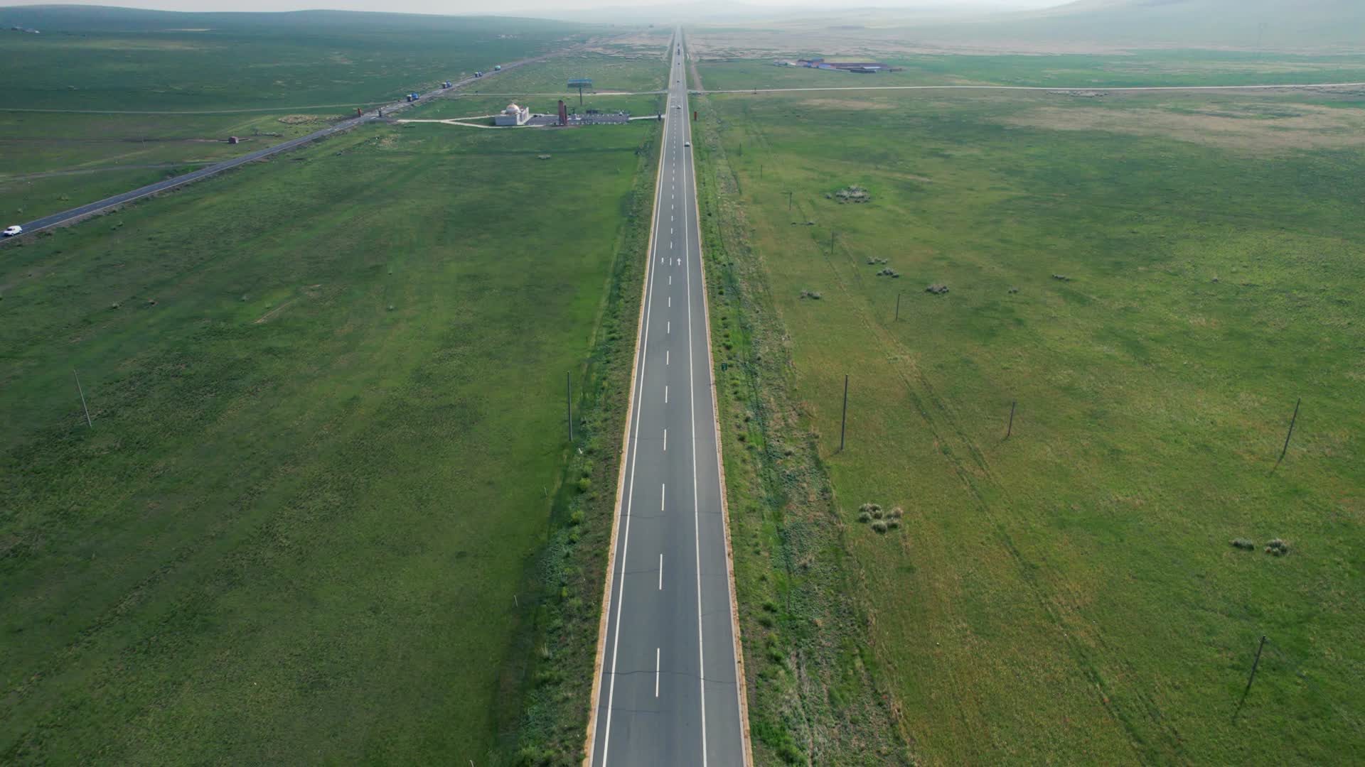 4k航拍在辽阔草原上冷清的公路和来往的车辆视频的预览图