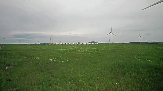 内蒙古锡林郭勒花开的草原上散落的蒙古包和大风车午后4k超高清航拍视频视频的预览图