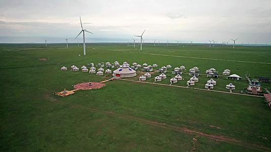 内蒙古锡林郭勒花开的草原上散落的蒙古包和大风车午后4k超高清航拍视频视频的预览图