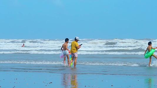 海边冲浪玩水的小孩实拍视频视频的预览图
