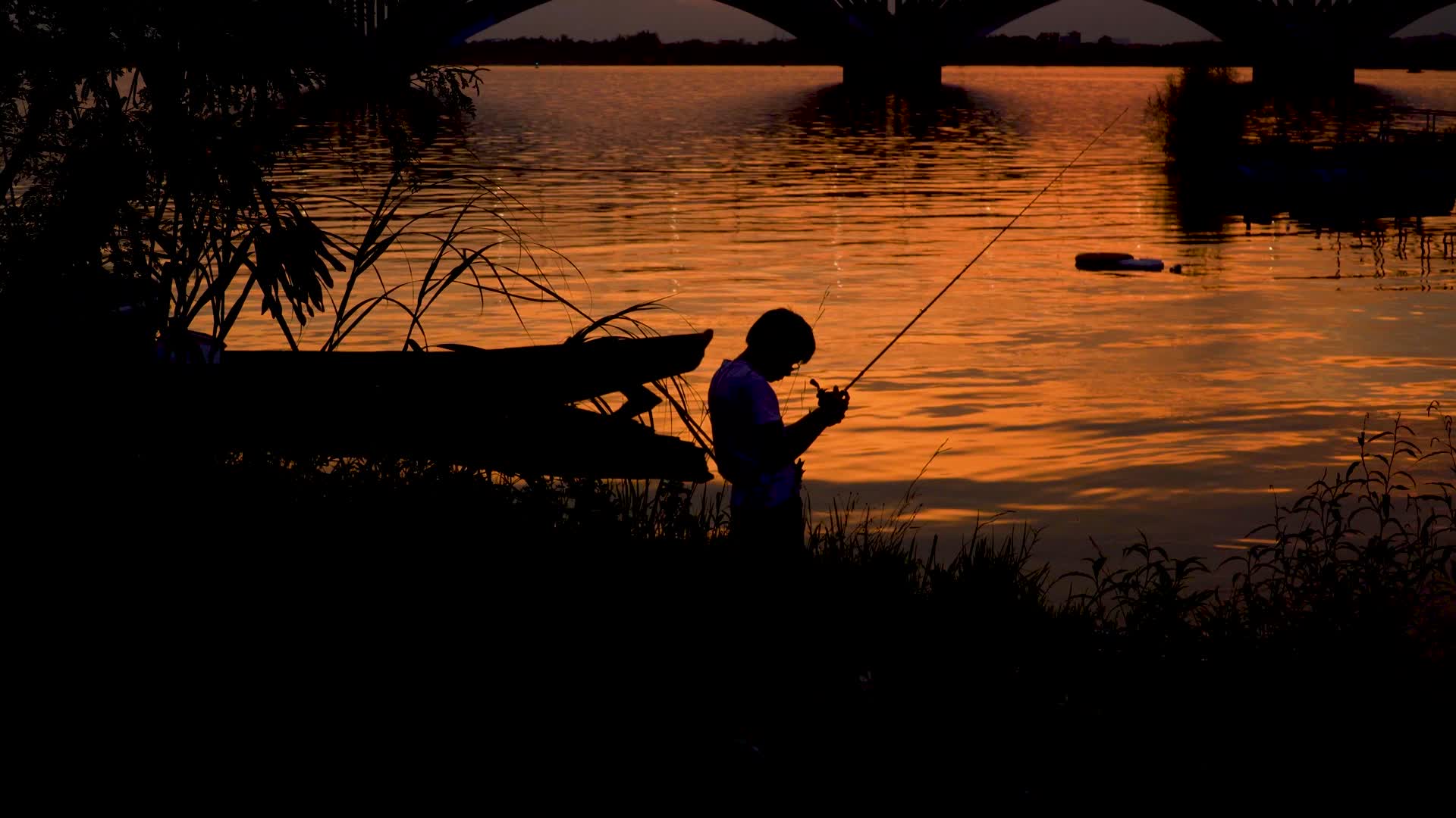 在夕阳下水边钓鱼的人视频的预览图