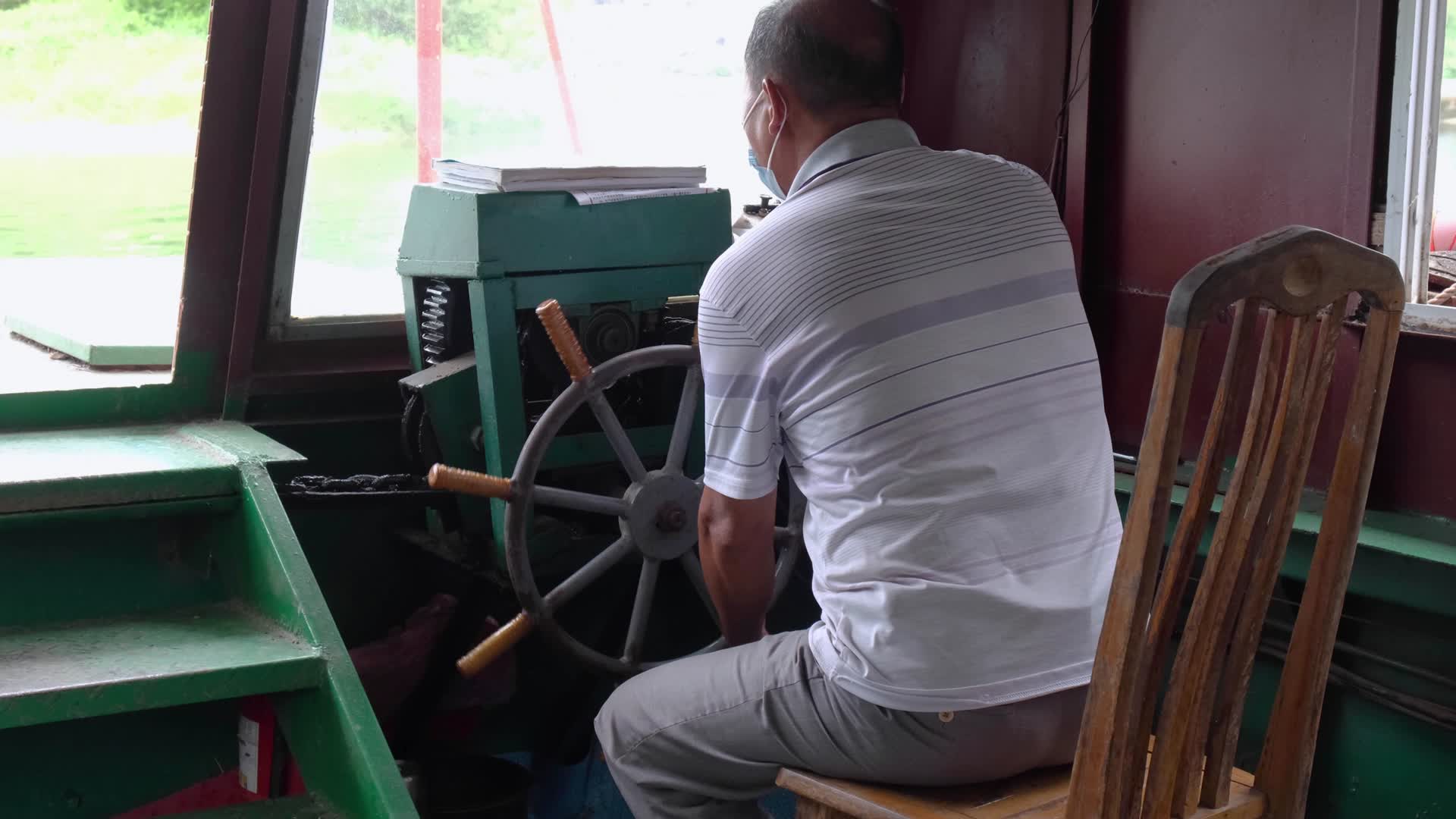操控摆渡船驾驶船舵轮船的中年男人视频的预览图