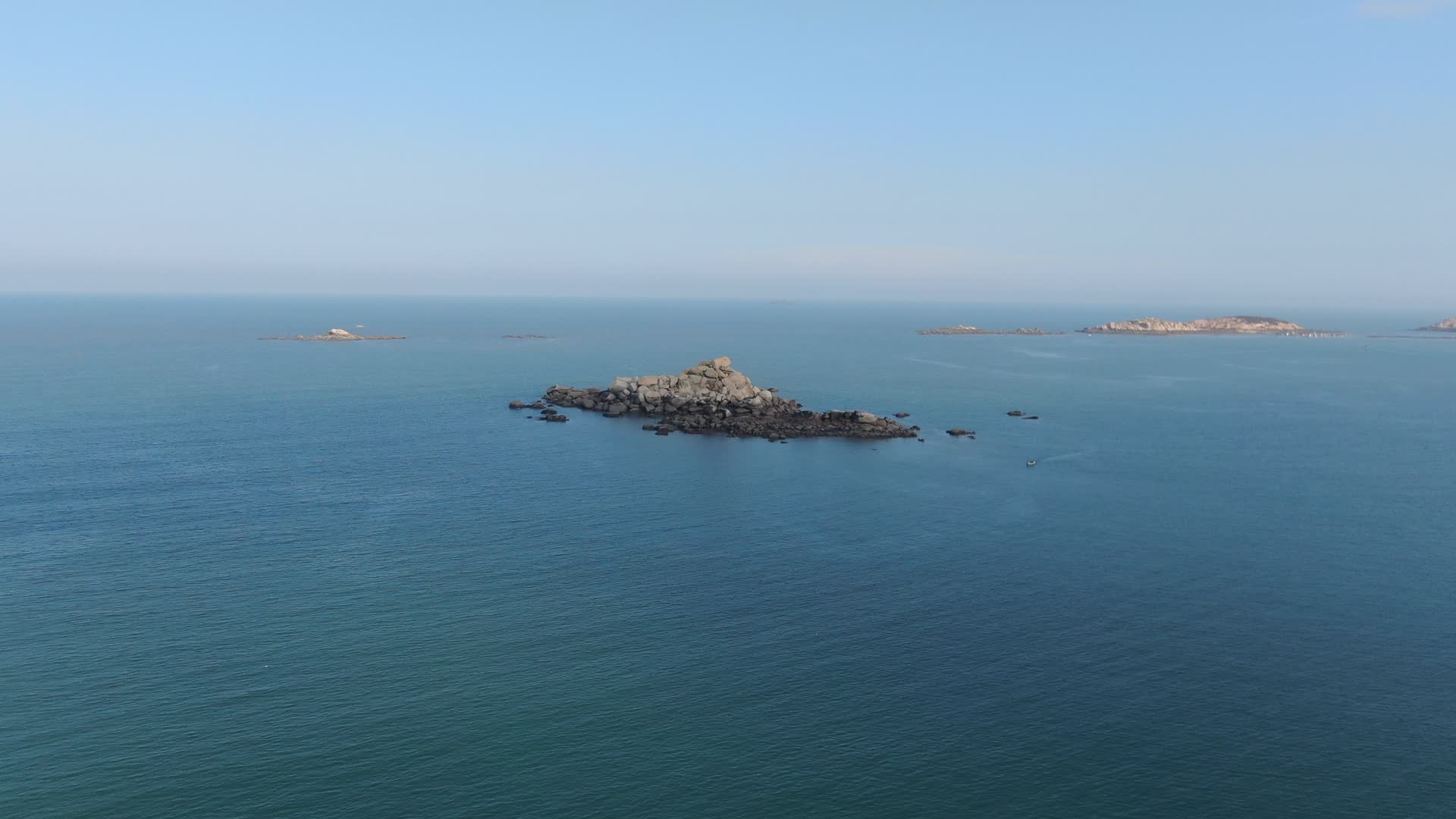 航拍蓝色海洋上礁石岛屿视频的预览图