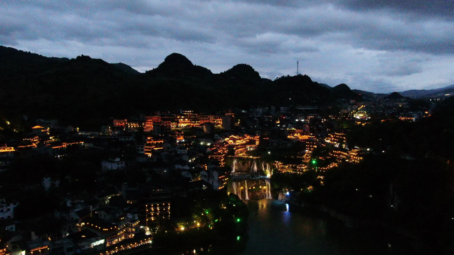 4K航拍瀑布上的古镇夜景视频的预览图