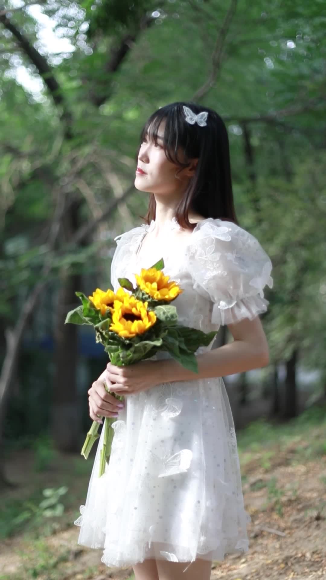穿着白色连衣裙的女孩拿着花在树林里写真拍摄视频的预览图