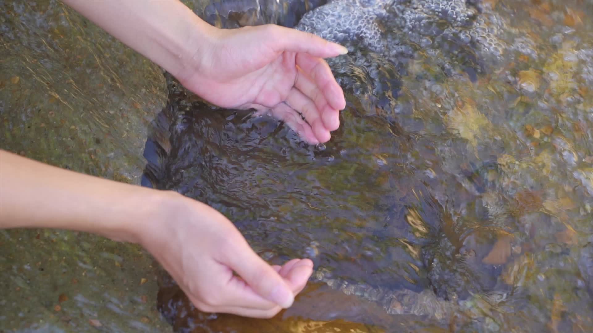 用手舀起溪水升格慢放视频的预览图