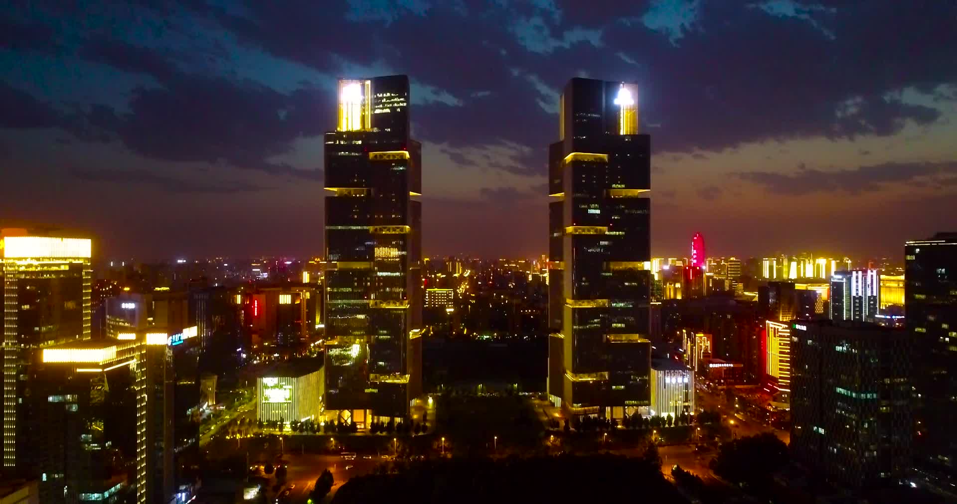 航拍郑州绿地双子塔夜景灯光和夕阳视频的预览图