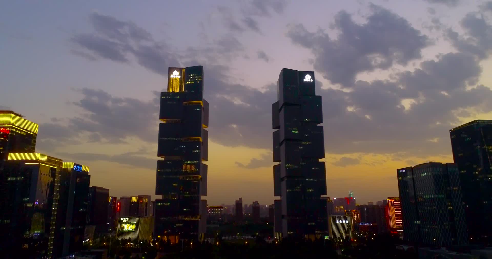航拍郑州绿地双子塔灯光渐亮视频的预览图