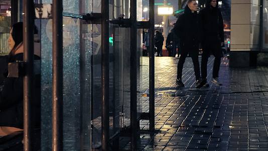 冬天傍晚雨后城市公交站等车的乘客视频的预览图