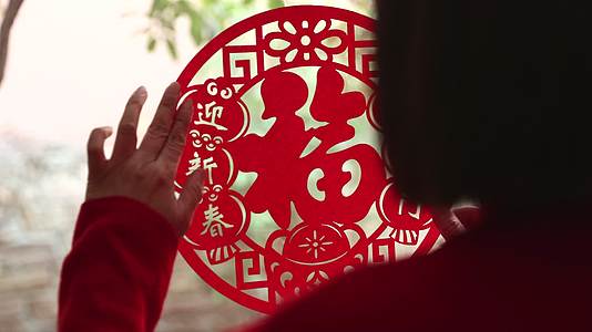 春节在家里贴窗花迎新年的中国女人视频的预览图