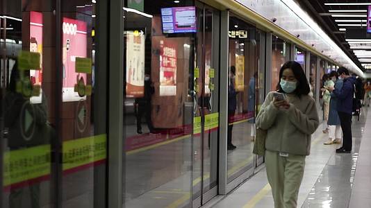 女孩走在地铁站玩手机视频的预览图