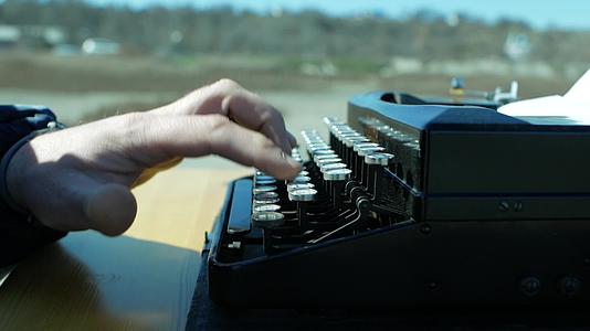 男子坐在户外使用老式复古打字机视频的预览图