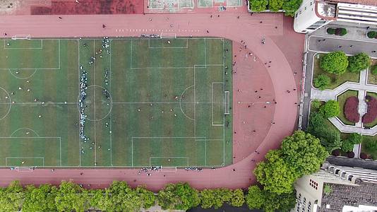 俯拍校园操场学生运动踢足球视频的预览图