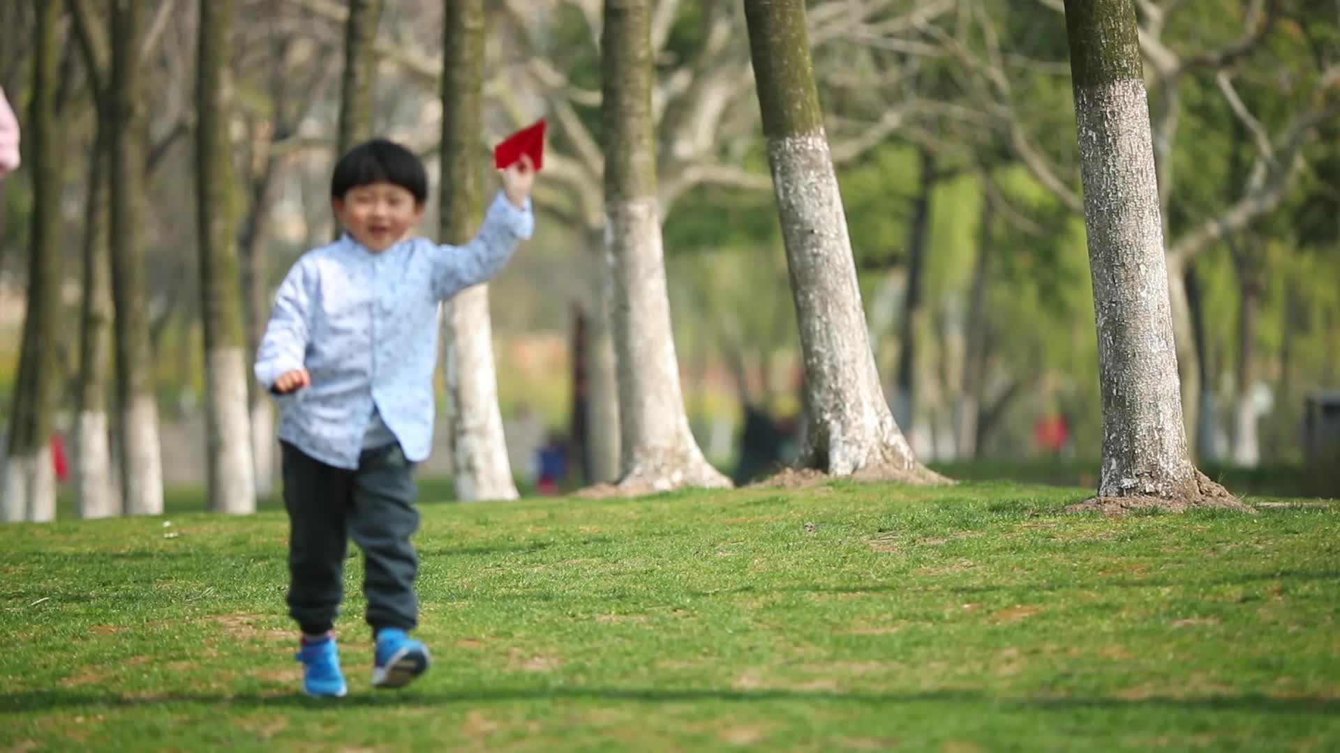 拿红色纸飞机的孩子在草地上奔跑视频的预览图