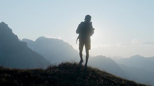 男子户外徒步逆光站在山顶视频的预览图