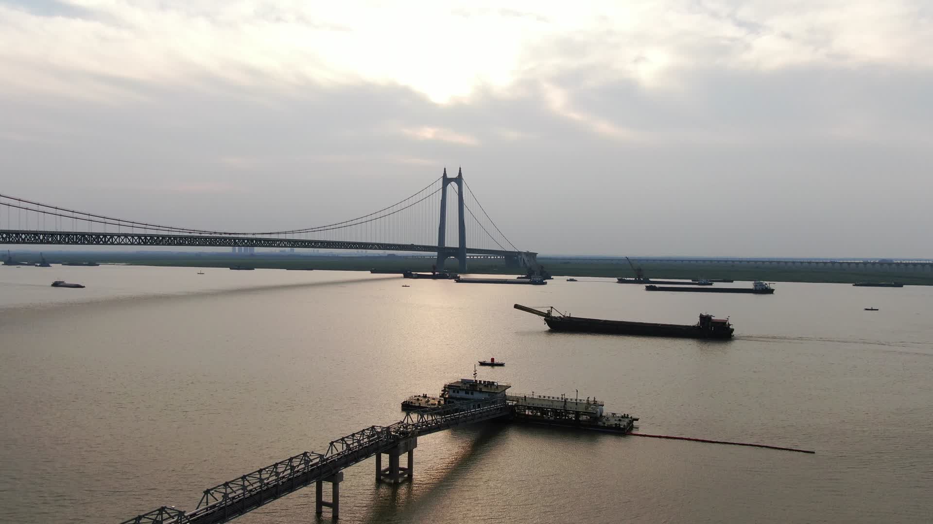 航拍夕阳下的城市跨河大桥轮船划过视频的预览图