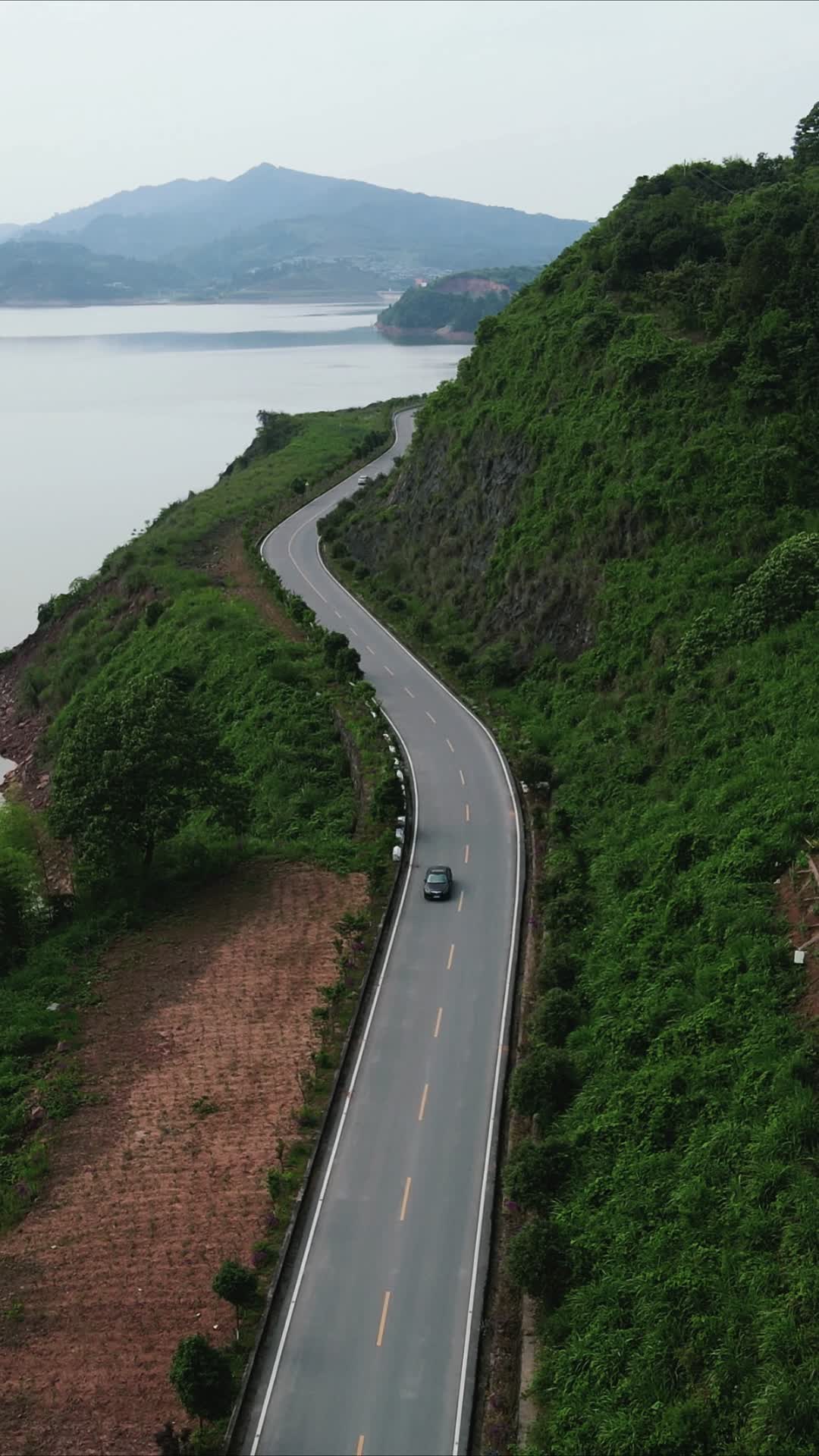 航拍湖边公路小车行驶竖屏视频的预览图