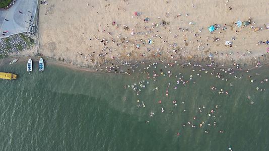 航拍夏季海滨浴场沙滩游玩人群视频的预览图