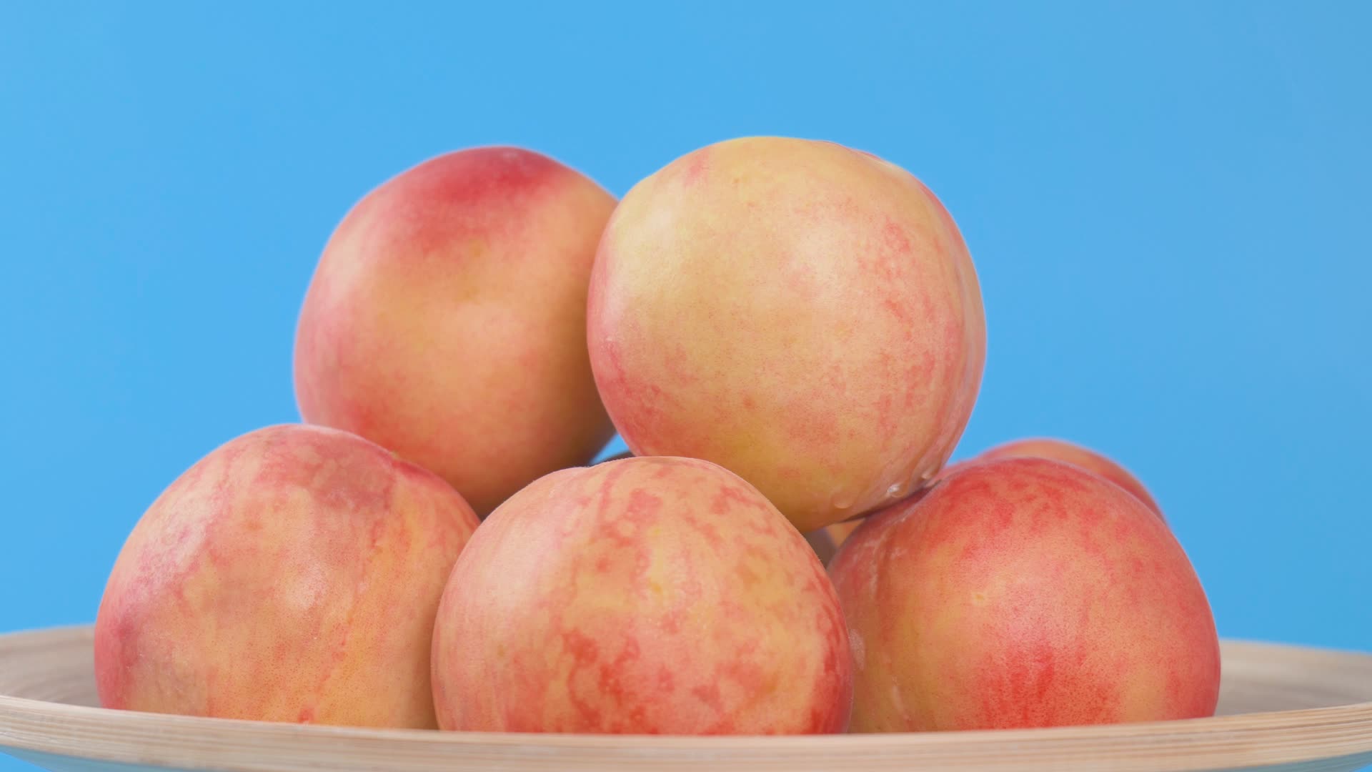 蓝色背景水蜜桃特写实拍素材粉色桃子水果4K视频视频的预览图