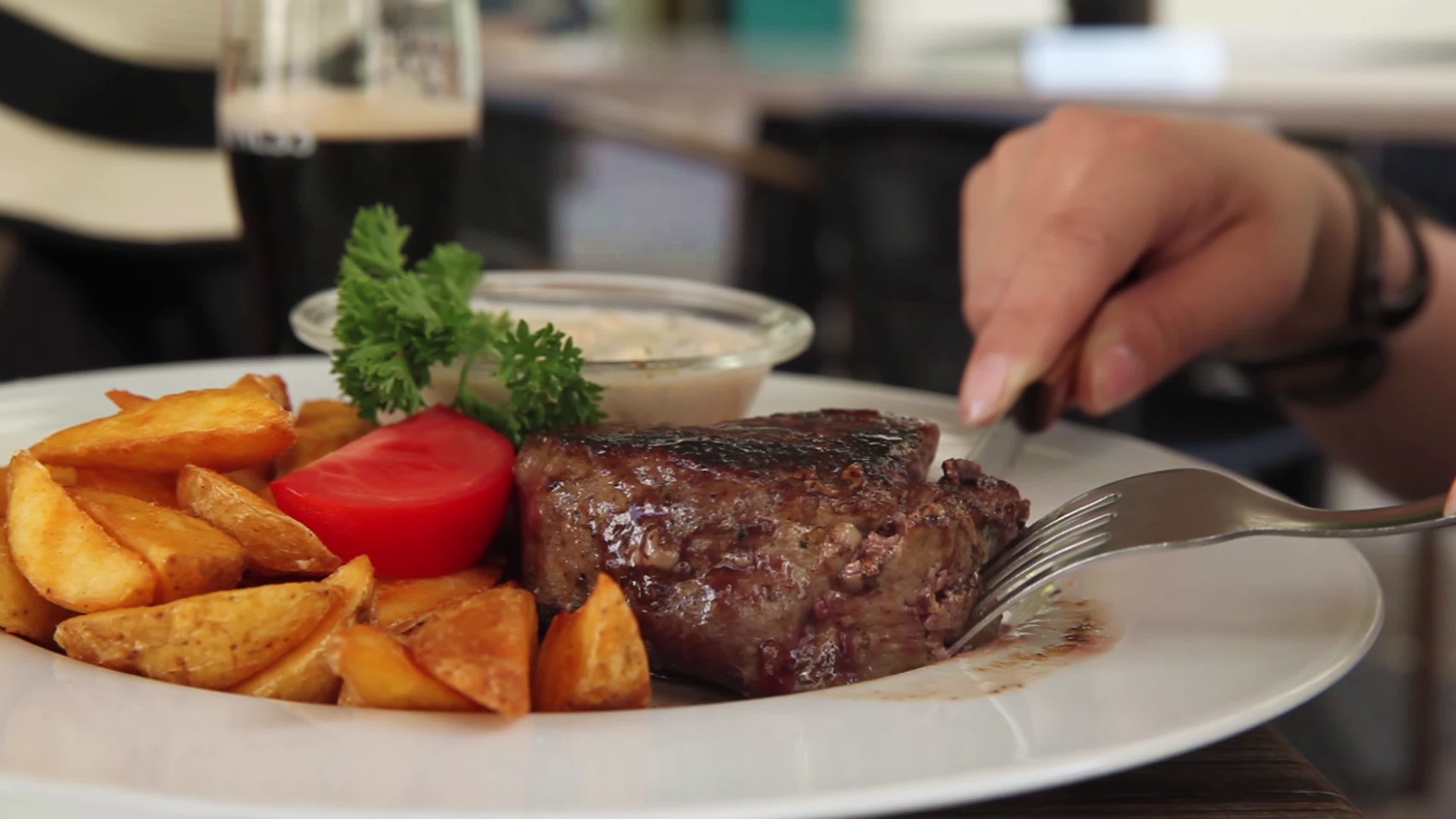 一个女人用餐刀和叉吃牛排特写视频的预览图