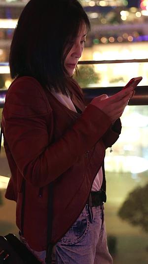 一个女人夜晚在户外街道上使用手机视频的预览图