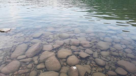 河岸水花拍打鹅卵石清澈见底背景视频的预览图