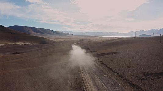 航拍越野车行驶在西藏阿里无人区的荒漠中车后扬起尘烟视频的预览图