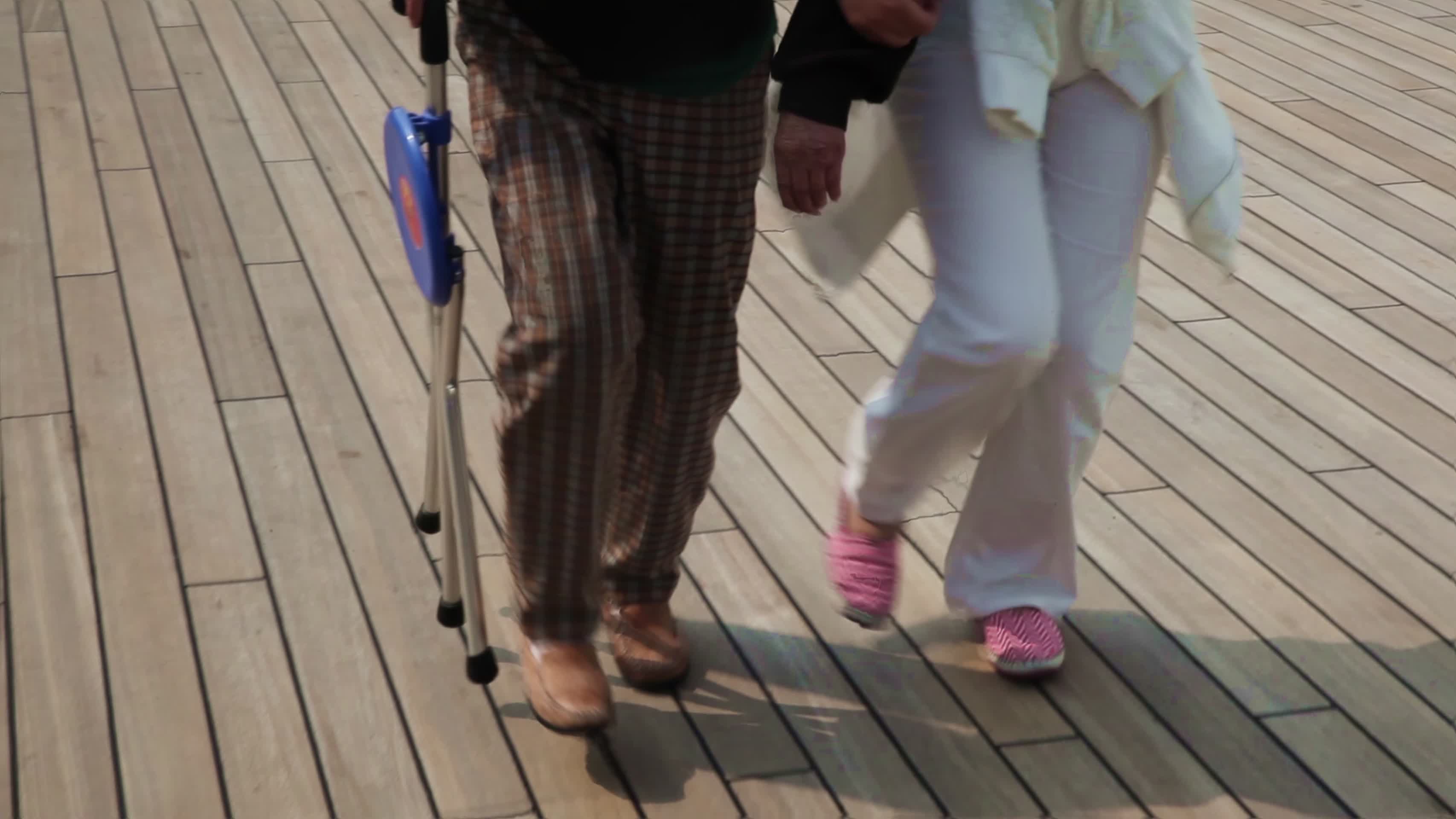 手拿手杖的老年女人在女儿帮助下散步视频的预览图