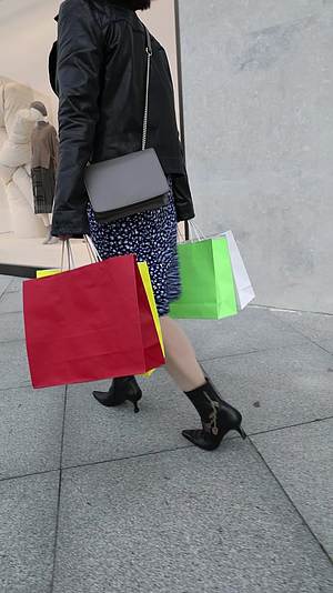 手拿购物袋走过商店橱窗的时尚女人慢镜视频的预览图