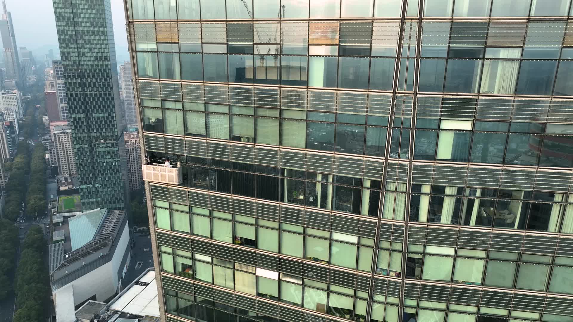 航拍在高楼外清洁外立面的工人视频的预览图