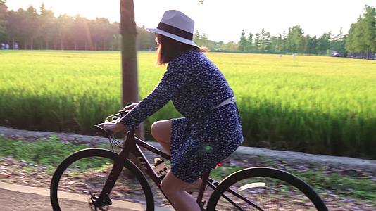 一个时尚女人在黄昏乡间小路骑自行车合集视频的预览图