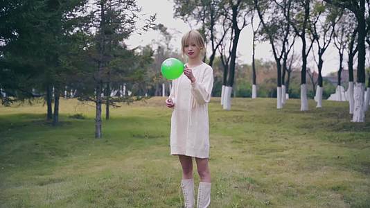 女生草坪上愉悦拍气球视频的预览图