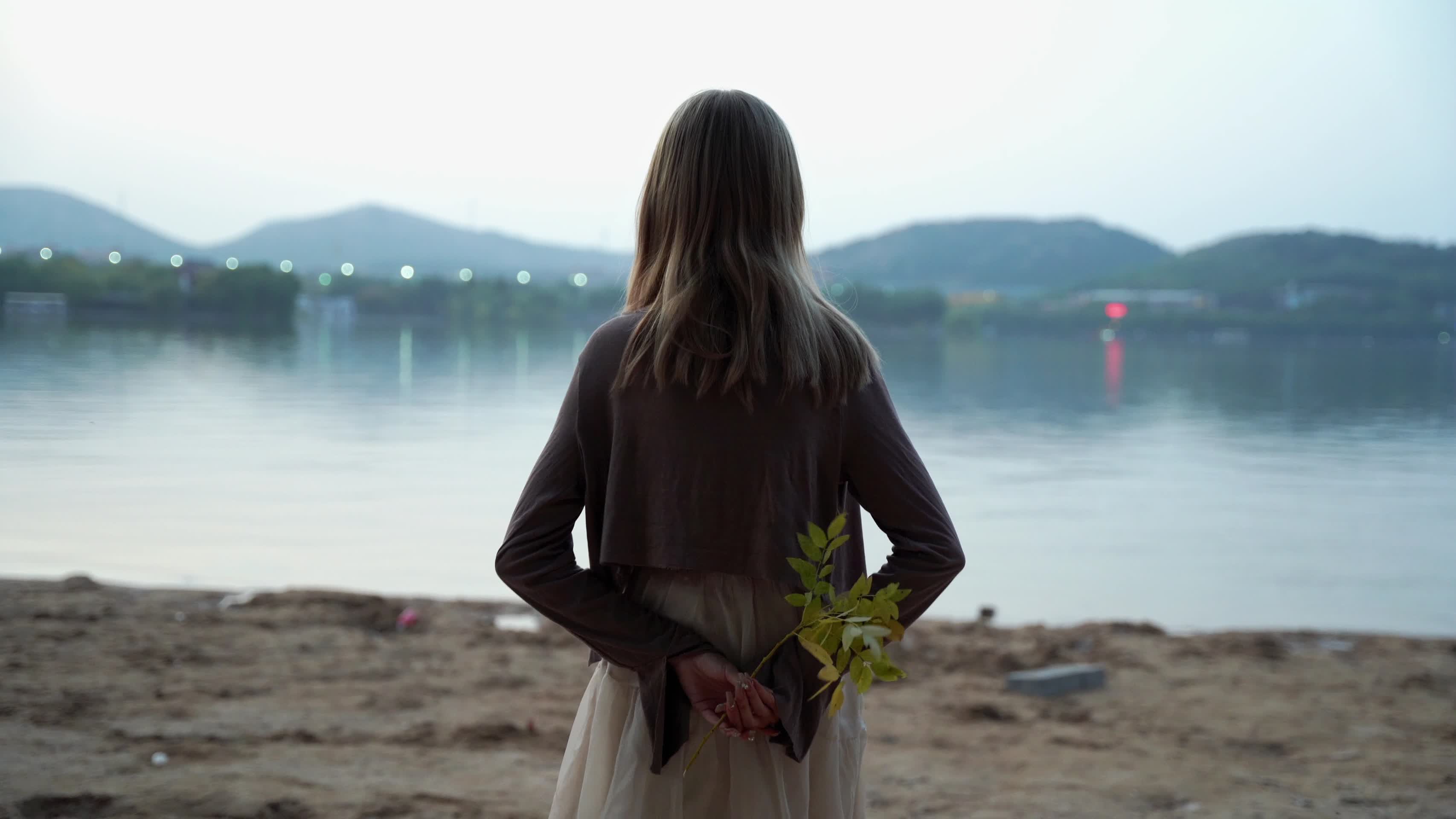女生拿花径直走向湖边视频的预览图