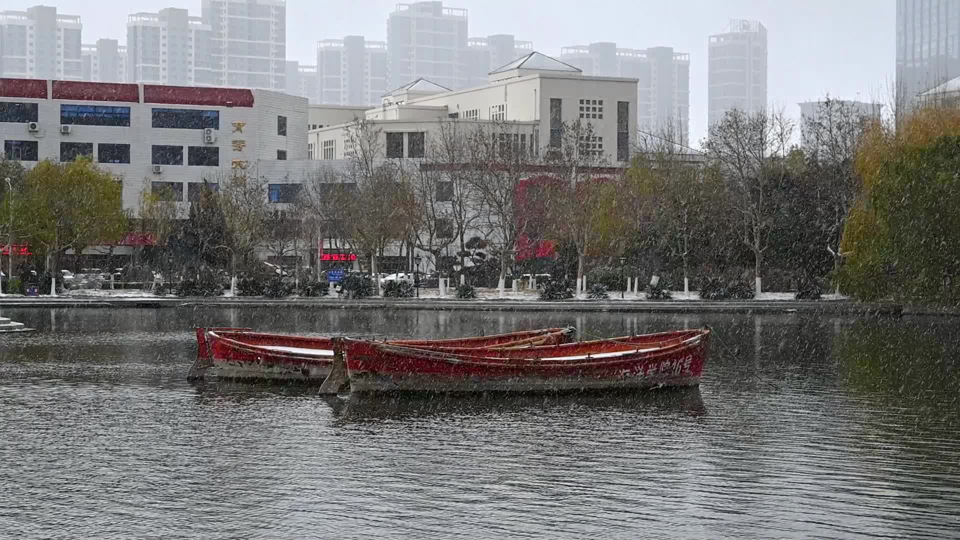 冬天初雪大雪纷飞湖泊上漂浮红船视频的预览图